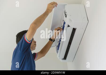 Klimaanlagen-Werkstätten in blauer Uniform prüfen und reparieren die an der Wand hängende Luft. Stockfoto