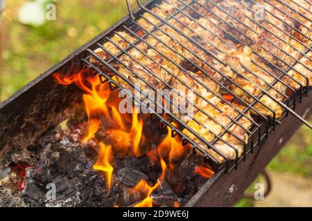 Gegrilltes Hähnchen auf dem Grill. ProzessKochen Hähnchenbeine auf einem Grill im Freien Flammen und Rauch auf dem Hintergrund. Stockfoto
