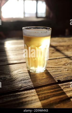 Bierkrug mit Licht auf Holztisch Stockfoto