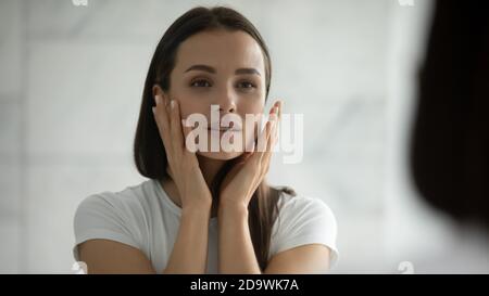 Spiegelreflexion der hübschen jungen Frau visuell Überprüfung der Hautgesundheit Stockfoto