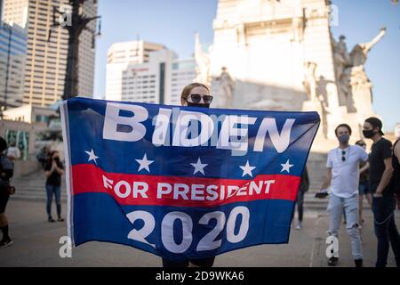 Indianapolis, Usa. November 2020. Eine Frau mit einer großen 'Biden Harris'-Flagge, während sie Gesichtsmasken trägt, feiert am Monument Circle in der Innenstadt von Indianapolis, nachdem der ehemalige Vizepräsident Joe Biden zum Sieger der Präsidentschaftswahl 2020 erklärt wurde, nachdem er den amtierenden US-Präsidenten Donald Trump besiegt hatte, um zum 46. Präsidenten zu werden Die Vereinigten Staaten. Kredit: SOPA Images Limited/Alamy Live Nachrichten Stockfoto