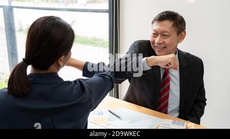 Zwei asiatische Kollegen vermeiden einen Händedruck beim Treffen im Büro Begrüßung mit stoßen Ellbogen während Coronavirus COVID-19 Epidemie im Büro, Social Stockfoto