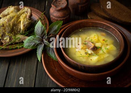 Rebhuhnsuppe mit Basilikum in einer rustikalen Schüssel auf dunkel Holztisch Stockfoto