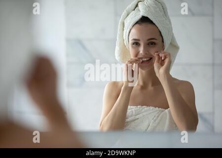 Angenehme Dame Reinigung der Zähne mit Zahnseide nach der morgendlichen Dusche Stockfoto