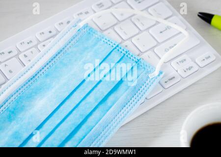 Anti-Virus-Maske, Computer-Tastatur, Kaffee, Bürobedarf, Pandemic Remote-Arbeit Konzept Coronavirus Stockfoto
