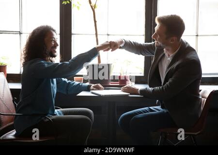 Zwei verschiedene Männer Freunde stoßen Fäuste über Tisch im Kaffeehaus Stockfoto