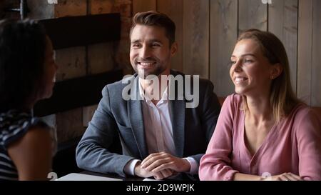 Verheiratetes Paar, das Vertrag mit Makler am Tisch im Café diskutiert Stockfoto