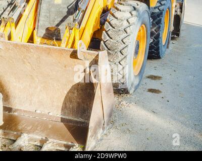 Fragment eines verschmutzten gelben Bulldozer mit Rädern und ein Schöpfkelle Stockfoto