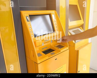 Man's Hand steckt eine ATM-Karte in einem Bankautomaten. Stockfoto