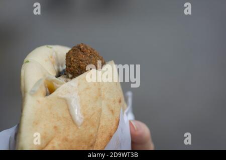 Nahaufnahme eines Pita-Brotes mit Falafel, einem typischen mittelöstlichen Essen, frittierten Bällchen aus gemahlenen Kichererbsen, die normalerweise mit Tahini-Sauce serviert werden Stockfoto