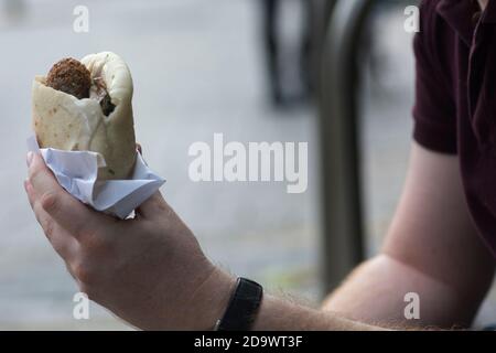 Mann hält ein Pita-Brot mit Falafel, einem typischen mittelöstlichen Essen, frittierte Kugeln aus gemahlenen Kichererbsen. Tel Aviv, Israel Stockfoto