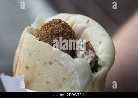 Nahaufnahme eines Pita-Brotes mit Falafel, einem typischen mittelöstlichen Essen, frittierten Bällchen aus gemahlenen Kichererbsen, die normalerweise mit Tahini-Sauce serviert werden Stockfoto