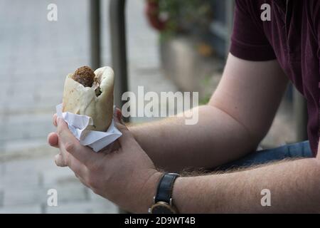 Mann hält ein Pita-Brot mit Falafel, einem typischen mittelöstlichen Essen, frittierte Kugeln aus gemahlenen Kichererbsen. Tel Aviv, Israel Stockfoto