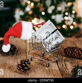 Nahaufnahme von Weihnachtsdekorationen, eine Mini-Shopping-Katze mit Geld darin, umgeben von Pinienzapfen Stockfoto