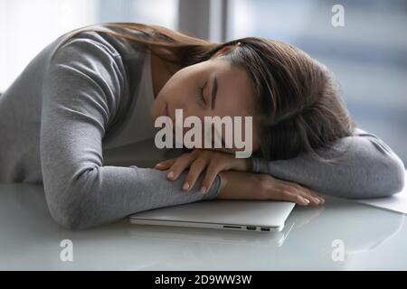 Müde Angestellte, die auf dem Schreibtisch schläft und den Kopf auf die Hände legt Stockfoto