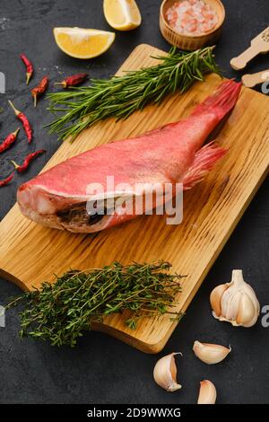 Frisch gefrorener kopfloser Meerbarsch mit Gewürzen und Kräutern Stockfoto