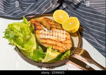 Teller gegrilltes Lachssteak mit Salat auf Holztisch Mit blauer Serviette Stockfoto