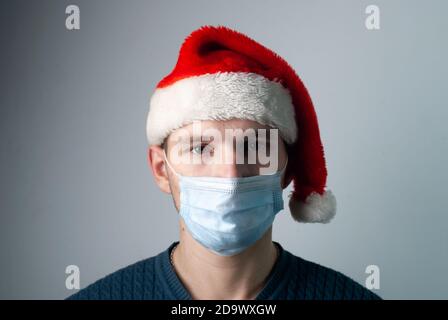 Trauriger junger Mann in medizinischer Maske, pandemisches Konzept für Weihnachten Stockfoto