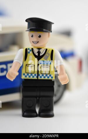 Eine Minifigur des Polizisten von Blox stand vor einem Spielzeug Polizeiauto Stockfoto