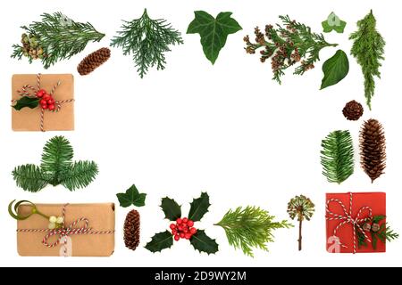 Weihnachtsumrandung mit umweltfreundlichen Geschenk verpackt Boxen & Winter Grün mit Stechpalme, Tannen, Efeu & Kiefer Kegel auf weiß. Weihnachten grünes Recycling-Konzept. Stockfoto