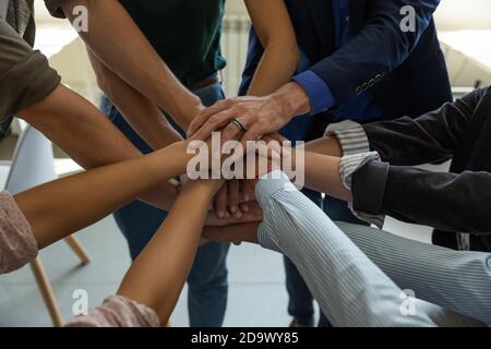 Motivierte verschiedene Geschäftsleute, die Hand zusammenlegen und Einheit demonstrieren Stockfoto