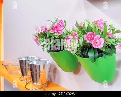 Vase mit Plastikblumen an der Wand hängt mit einem schönen Haus dekoriert. Stockfoto