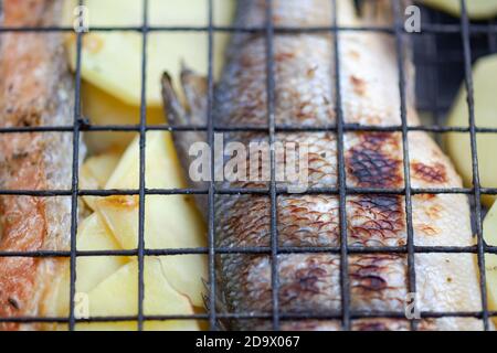 Gebratener Seebarsch mit Kartoffeln auf dem Grill Stockfoto