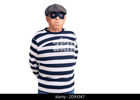 Senior schöner Mann trägt Einbrecher Maske und T-Shirt Puffing Wangen mit lustigen Gesicht. Mund mit Luft aufgeblasen, verrückte Ausdruck. Stockfoto
