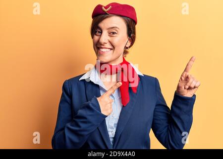 Junge schöne Frau trägt Stewardess Uniform lächelnd und Blick auf die Kamera zeigt mit zwei Händen und Fingern zur Seite. Stockfoto