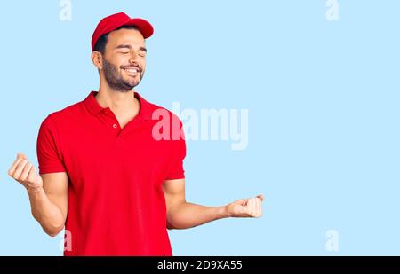 Junge gutaussehende hispanischen Mann trägt Lieferung Kurier Uniform sehr glücklich und aufgeregt tun Sieger Geste mit den Armen angehoben, lächelnd und schreiend für s. Stockfoto