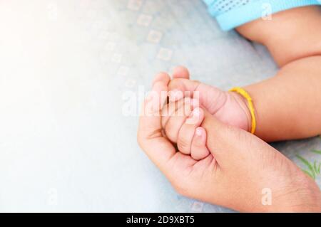 Die Hand der Mutter kadelt die Hand eines Babyhintergrunds für die Liebe und den Muttertag. Stockfoto