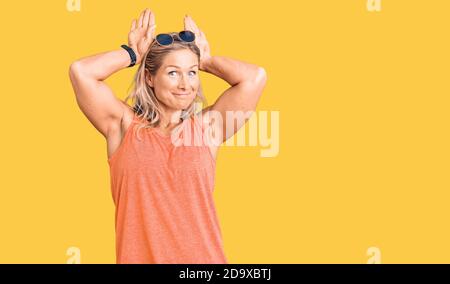 Mittelalter fit blonde Frau trägt lässige Sommerkleidung und Sonnenbrille tun Bunny Ohren Geste mit Händen Handflächen zynisch und skeptisch suchen. ost Stockfoto
