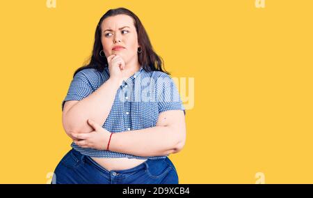 Junge plus size Frau tragen lässige Kleidung ernstes Gesicht denken über Frage mit der Hand auf dem Kinn, nachdenklich über verwirrende Idee Stockfoto