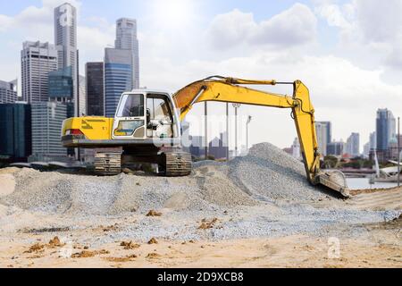 Bagger auf dem Hügel in der Stadt mit Wolkenkratzer Hintergrund geparkt. Stockfoto