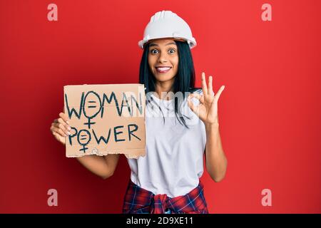 Junge afroamerikanische Frau trägt Architekt Hardhat halten Frau Macht Banner tun ok Zeichen mit Fingern, lächelnd freundlich gestikulieren ausgezeichnete sym Stockfoto