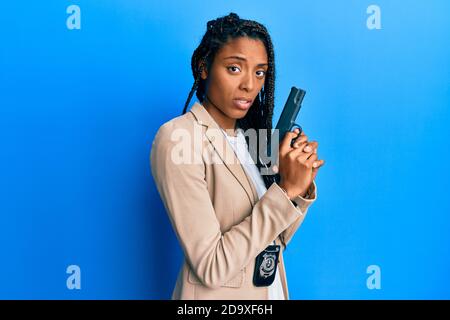 afroamerikanische Polizei Frau hält Waffe ahnungslos und verwirrt Ausdruck. Zweifel Konzept. Stockfoto