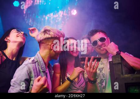 Junge Leute schnüffeln Drogen im Nachtclub mit bunten Laserlicht Stockfoto