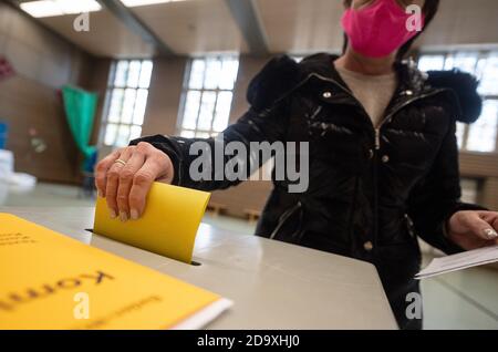 Stuttgart, Deutschland. November 2020. Eine Frau mit Mund- und Nasenschutzmaske stimmt in einem Wahllokal zur Wahl des neuen Oberbürgermeisters in Stuttgart ab. Eine mögliche Abwahl findet am 29. November 2020 statt. Quelle: Sebastian Gollnow/dpa/Alamy Live News Stockfoto