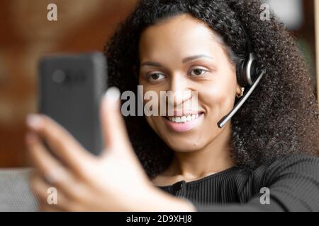 Lächelnde afroamerikanische Frau im Headset mit Online-Gespräch. Nahaufnahme. Stockfoto