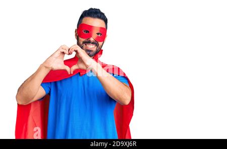 Junge hispanic Mann trägt Superhelden Kostüm lächelnd in der Liebe zeigt Herz Symbol und Form mit Händen. Romantisches Konzept. Stockfoto
