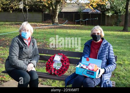 Biggin Hill, Großbritannien, 8. November 2020, Trotz Lockdown Menschen besuchen einen Gedenkdienst in Biggin Hill Kent. Zwei Damen, die das Fraueninstitut vertreten, sitzen auf einer Bank, die Mohnblumen verkauft, bevor sie einen Kranz niederlegen.Quelle: Keith Larby/Alamy Live News Stockfoto