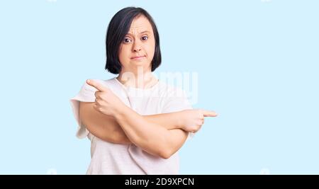 Brunette Frau mit Down-Syndrom tragen casual weißen T-Shirt zeigt auf beiden Seiten mit Fingern, andere Richtung nicht einverstanden Stockfoto