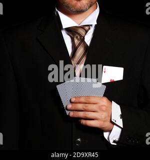 Mann professionell gekleidet mit dem Ass der Herzen in seinem Brusttasche und Keulen-Ass im Ärmel Stockfoto