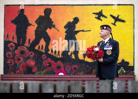 Veteran Charlie MacVicar, der 23 Jahre lang bei Royal Scots (Edinburgh Unit) arbeitete, zollt am Remembrance Sunday seinen Respekt im Royal British Legion Remembrance Garden in Grangemouth, dem ehemaligen Standort des Flughafens Grangemouth, wo Spitfire-Piloten während des Zweiten Weltkriegs trainierten. Stockfoto