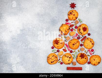 Kulinarischer Hintergrund von Keksen mit Preiselbeeren, weißer Schokolade, Mandeln und Gewürzen in Form eines Weihnachtsbaumes. Zusammensetzung von Keksen, Cinnamo Stockfoto