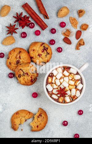 Heiße Schokolade (Kaffee, Kakao) mit Marshmallows in einer weißen Tasse und hausgemachte Kekse mit Preiselbeeren, Mandeln und Gewürzen (Zimt, Sternanis, Kardam Stockfoto