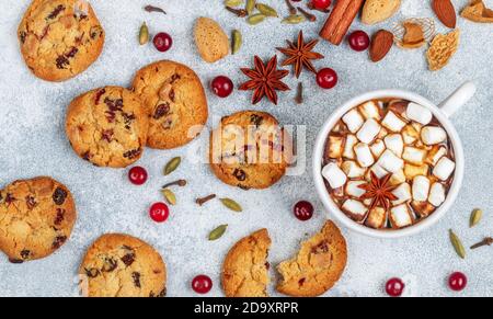 Heiße Schokolade (Kaffee, Kakao) mit Marshmallows in einer weißen Tasse und hausgemachte Kekse mit Preiselbeeren, Mandeln und Gewürzen (Zimt, Sternanis, Kardam Stockfoto