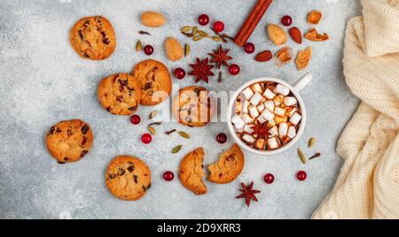 Heiße Schokolade (Kaffee, Kakao) mit Marshmallows in einer weißen Tasse und hausgemachte Kekse mit Preiselbeeren, Mandeln und Gewürzen (Zimt, Sternanis, Kardam Stockfoto