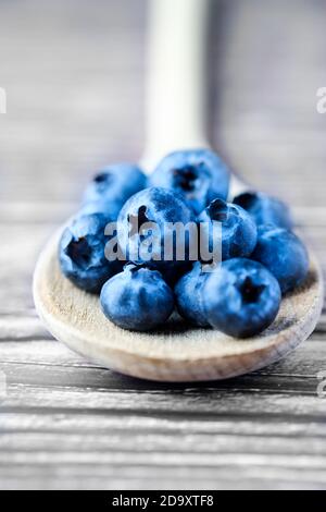 Frisch, Heidelbeeren, Cyanococcus, auf einem Holzlöffel. Die Heidelbeere ist eine reiche Quelle von Antioxidantien und reich an Vitaminen c und K. Stockfoto