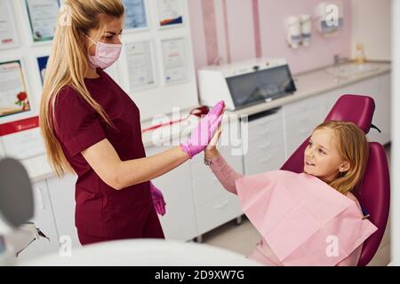 Gibt hohe fünf. Kleines Mädchen Besuch Zahnarzt in der Klinik. Konzeption der Stomatologie Stockfoto